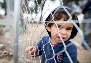 epa05199233 A refugee child stands by the border fence in the refugee camp at the Greek-Macedonian border near Idomeni, Greece, 07 March 2016. Media and humanitarian organizations estimate that the number of migrants stuck at the Greek-Macedonian border crossing has swelled to 14,000. Macedonia has closed its borders to the wave of refugees wanting to pass through its territory to reach richer nations in western and northern Europe, straining bilateral ties with Greece. The Greek Foreign Ministry has threatened Macedonia with unspecified serious consequences if it does not let the refugees pass through. EPA/KAY NIETFELD